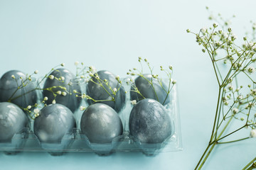 Delicate blue Easter eggs among the flowers of gypsophila on a blue background
