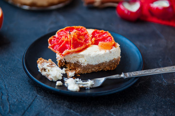 Plate with piece of baked cheesecake with red grapefruit slices and vintage fork on the black stone background with ingredients. Selective focus, space for text.