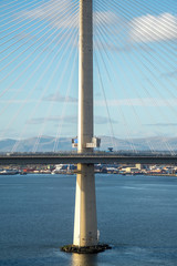 Fototapeta na wymiar The new Queensferry Crossing Bridge, viewed from the west footpatch of the old Forth Road Bridge, showing a tower and the cable-stayed construction. Rosyth in the background