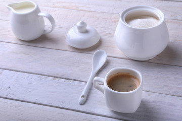 Cup of hot coffee espresso, coffee beans, jug of milk, and bowl with sugar on white background for copy space. Coffee concept.
