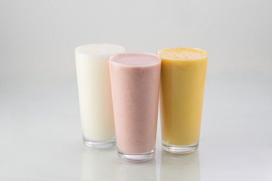 Set of three Indian traditional yogurt milk shakes lassi or smoothie isolated on white background - plain, banana and strawberry flavored