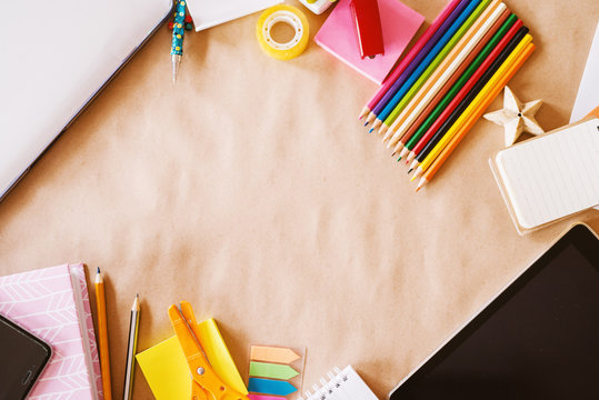 Top view of kids school desk set up with wooden crayons for art and modern technologies for browsing.