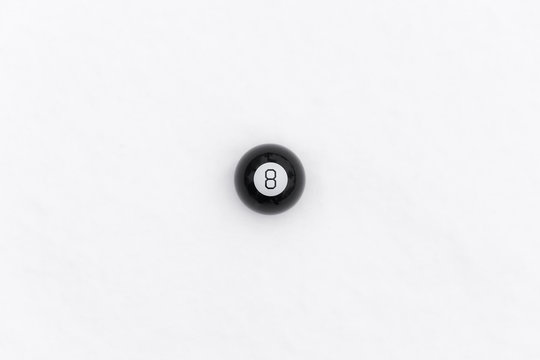 Billiards ball with number eight 8 laying on the white snowy background