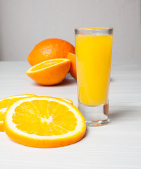 Orange juice glass and orange slices on a light wood background