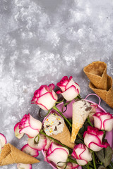 Composition of ice cream waffles with roses bouquets on a stone background