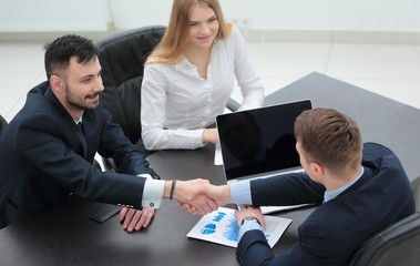 handshake financial partners sitting at the table
