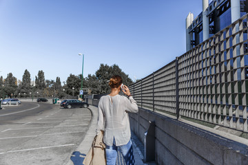 Business woman talking on her mobile phone, while walking down the street