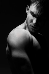 Fototapeta premium Duży i silny muskularny mężczyzna w pozowaniu przy słabym świetle. Model fitness lub trener pokazujący bicepsy, barki i klatkę piersiową. Wściekły wojownik mma lub kulturysta jest gotowy do skopania tyłka.