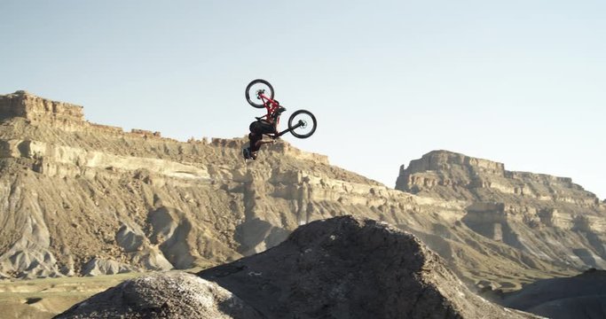 Slow motion, mountain biker does backflip in canyon