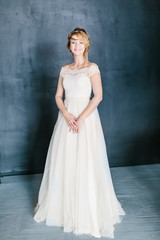 Fototapeta premium Young beautiful bride with a beautiful diadem in the hair poses sitting on the chair on dark background.