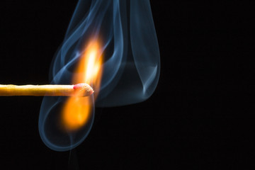 Match stick burning stick with smoke on a black background
