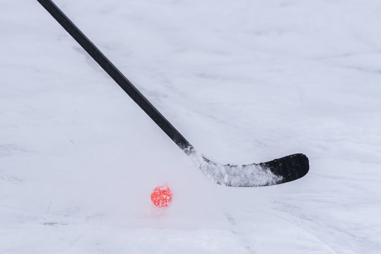 close-up of a hockey stick with an orange ball
