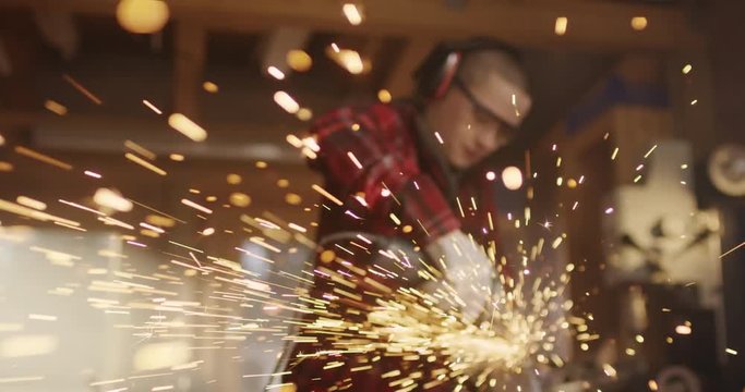 Focus rack into short haired woman working with angle grinder ; Many sparks