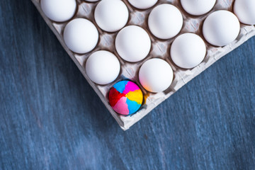 Colorful eggs and a cardboard box with white eggs