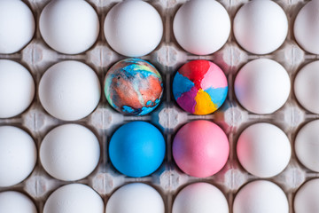 Colorful eggs and a cardboard box with white eggs