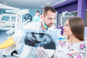 Obraz premium Doctor talking with patient and showing a radiograph in stomatology clinic. Dentist concept.