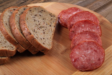 On the cutting board is sliced ​​bread and sliced ​​sausage. A table of an old tree.
