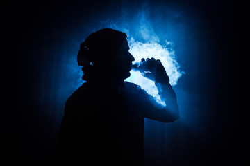 Vaping man holding a mod. A cloud of vapor. Black background. Vaping an electronic cigarette with a...