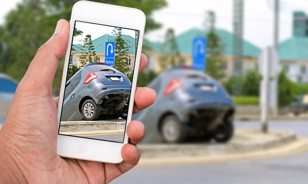Close up hand of man holding smartphone and take photo of car accident
