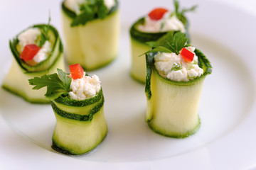 Rolls of zucchini stuffed with cheese and chives and red paprika.