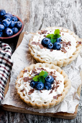 Delicious  tarts with cream and fresh blueberry on wooden table