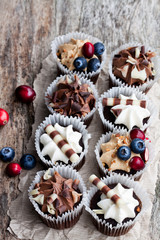 Chocolate  mini cupcakes with chocolate and berries on wooden table