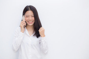 Beautiful asian young businesswoman excited and glad of success taking mobile phone on cement background, career freelance business concept.