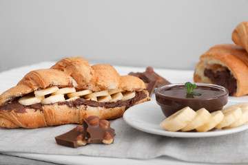 Tasty croissant with banana and chocolate sauce on table