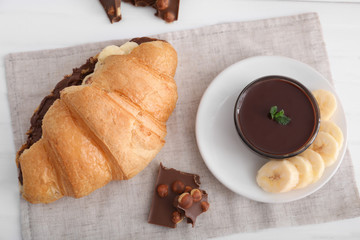 Tasty croissant with banana and chocolate sauce on table