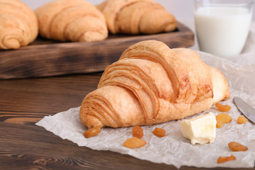 Tasty croissant with butter and raisins on wooden table