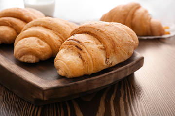 Tasty croissants on wooden tray, closeup