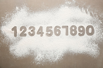 Silhouettes of Arabic numerals on scattered flour