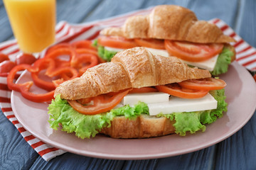 Plate with tasty croissant sandwiches on table