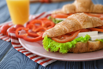 Plate with tasty croissant sandwich on table