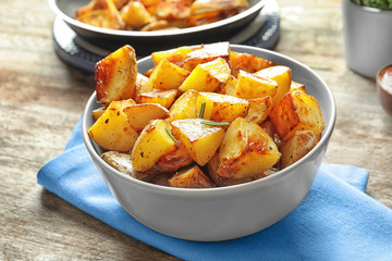 Bowl with tasty potato wedges on table