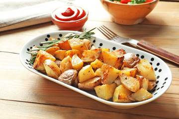 Plate with tasty potato wedges on table