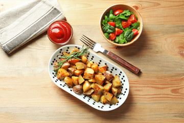 Plate with tasty potato wedges and tomato sauce on table