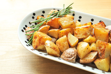 Plate with tasty potato wedges on table