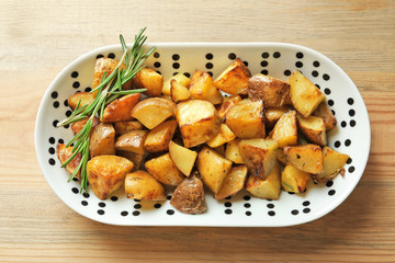 Plate with tasty potato wedges on table