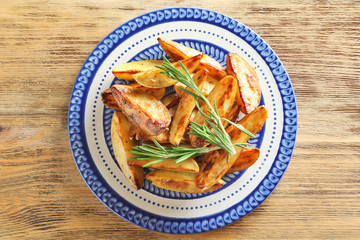 Plate with tasty potato wedges on table