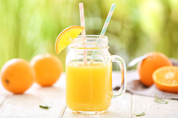 Mason jar with fresh orange juice on table