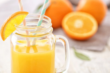 Mason jar with fresh orange juice on table, closeup