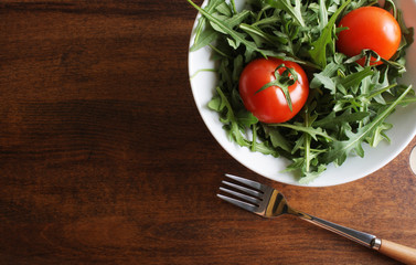 salad of rucola tomato on a wooden background
