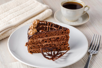 The slice of chocolate cake Prague with chocolate buttercreamy frosting on a  plate. Homemade baking. Close-up view.