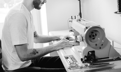 Stylish man works on a sewing machine