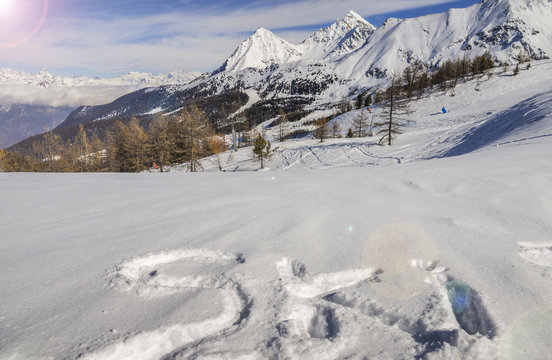Ski written on fresh powder snow with Alps background