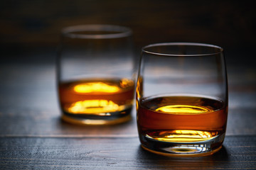 Two glasses of old whiskey on wooden table