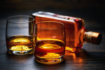 Wooden table with two shots of whiskey and full bottle