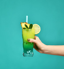 Blue and green tropical alcohol cocktail drink in woman hand 