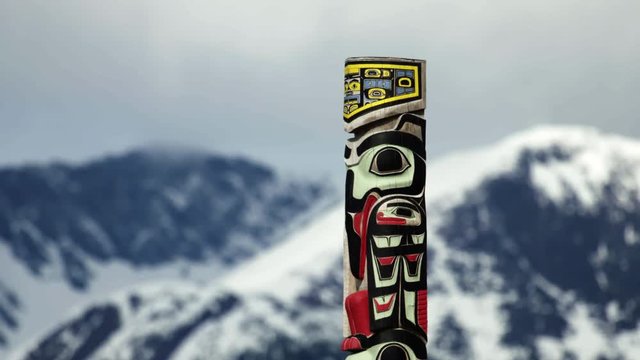 Traditional Alaskan totem pole and mountains